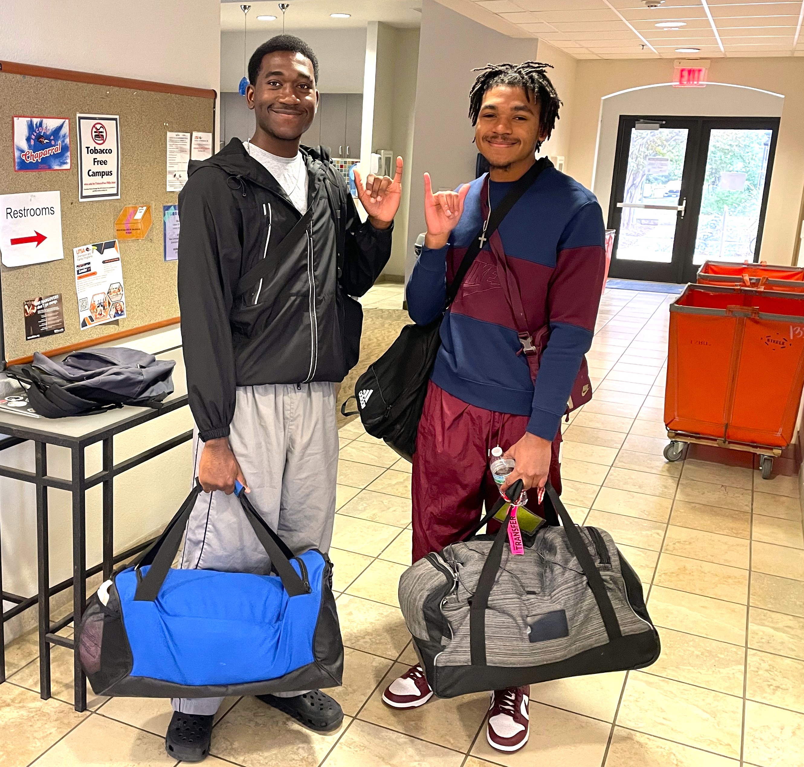 Students with duffel bags move into a residence hall.