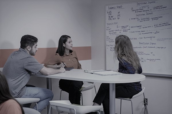 Students in a study room discussing notes written on a whiteboard