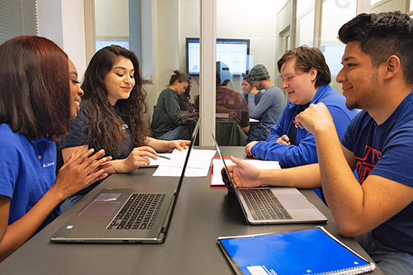 Students sitting in a study room with their laptops studying