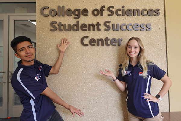 Students standing in front of the college of sciences student success center sign