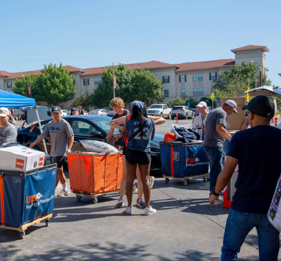 Students using housing carts to move their belongings from cars